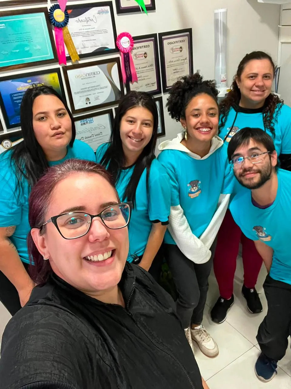 Equipe da PetTopia Ipês em frente à parede de certificados